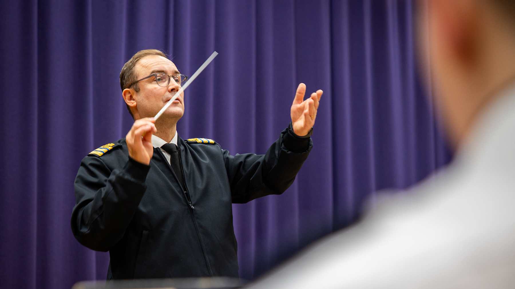 Laivaston soittokunnan kapellimestari johtaa orkesteria tummansinisessä uniformussaan.