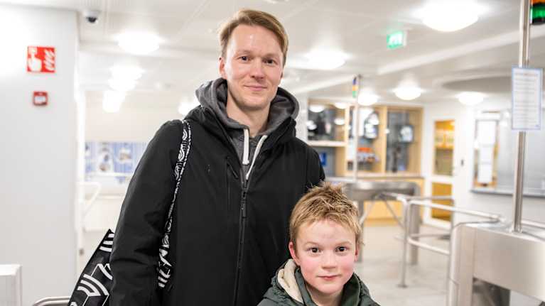 Isä ja poika ulkovaatteissa uimahallin portilla.