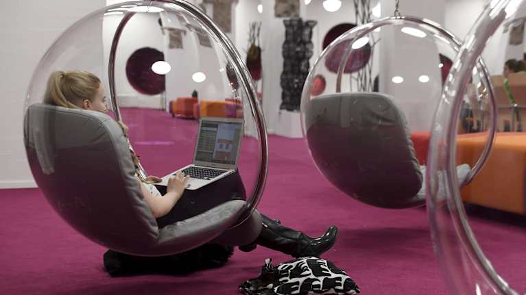 Opiskelija istuu läppäri sylissä pallotuolissa Aalto yliopiston tiloissa.