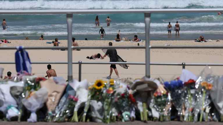 Kukkakimppuja Bondi Beachin rantakadulla. Taustalla näkyy ihmisiä rannalla ja surffari.