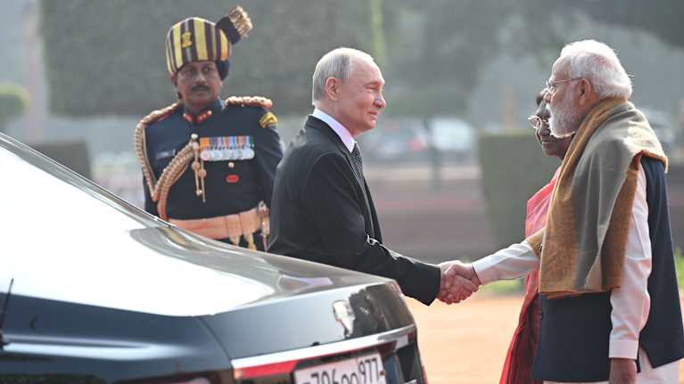 Vladimir Putin kättelee Narendra Modia. Edustalla auto.