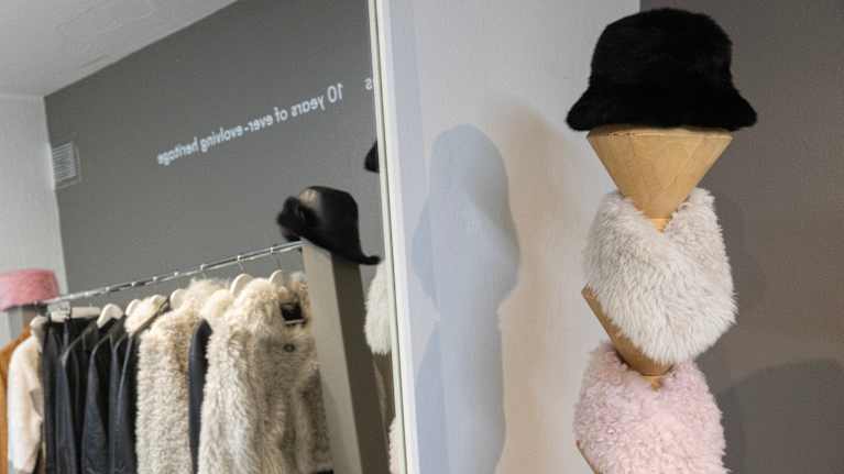 Näyttelytila, jossa on esillä turkistuotteita, kuten hattuja ja takkeja.