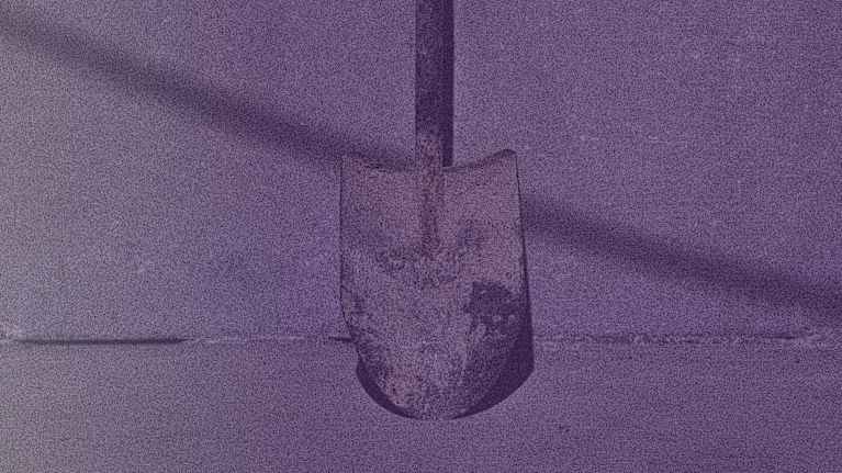 Kuvassa on lapio, jonka kärki nojaa seinää vasten. Kuva on sävytetty violetiksi.