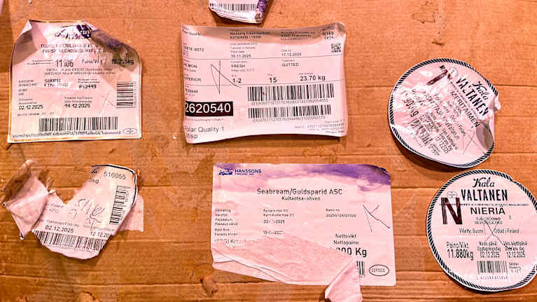 Kalapakettien tarroja pahvin päällä.