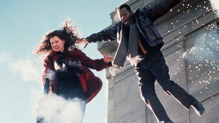 Still-kuva elokuvasta The Long Kiss Goodnight. Näyttelijät ja Geena Davis ja Samuel L. Jackson putoavat katolta räjähdyksien saattelemana.