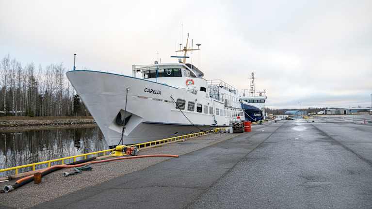 Kuvassa näkyy kaksi laivaa laiturissa talvisessa satamassa. Etualalla on valkoinen laiva nimeltä "Carelia". Taustalla näkyy toinen laiva.