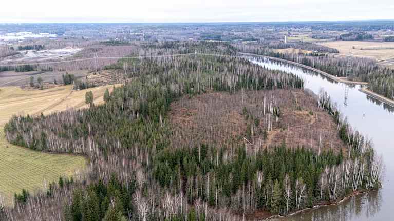Ilmakuva Saimaan kanavasta, jossa näkyy ympäröivää metsää ja peltoja. Kanava mutkittelee maisemassa.