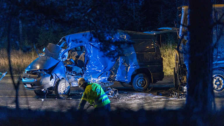 Onnettomuudessa pahoin rusentunut pakettiauto, jonka takana on osin vaurioitunut rekka. Tiellä neonkeltaisiin vaatteisiin pukeutunut pelastaja.