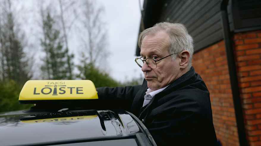 Henkilö asentaa taksi-kylttiä auton katolle.