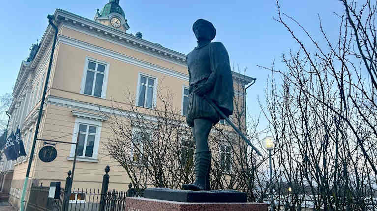 Juhana-herttuan näköispatsas on talvisen puistikon edessä.