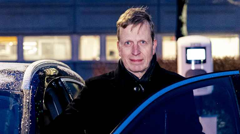 Vaaleatukkainen mies katsoo kohti kameraa. Taustalla näkyy pimeä parkkipaikka.