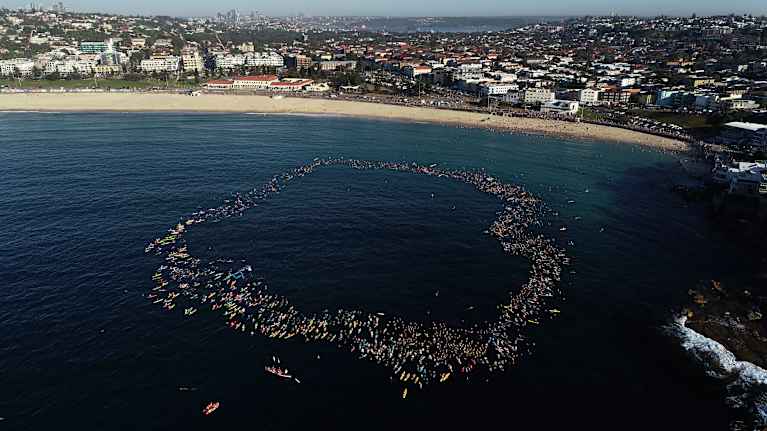 Ilmakuva Sydneyn Bondi Beachilta. Vedessä veneitä kokoontuneena yhteen.