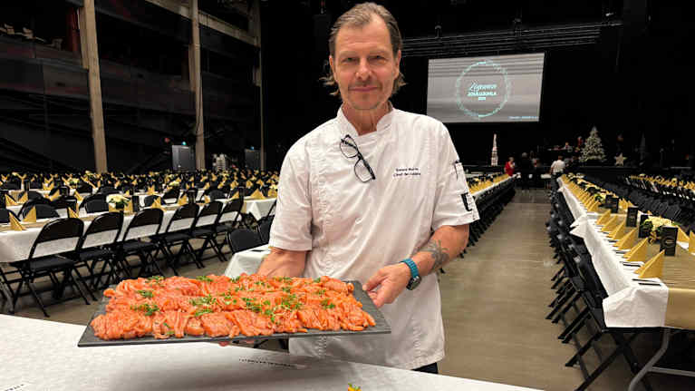 Valkoiseen kokkitakkiin pukeutunut mies esittelee graavikalatarjotinta.