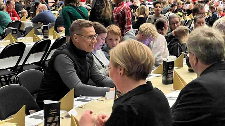 Mies istuu ja keskustelee ruokapöydässä-