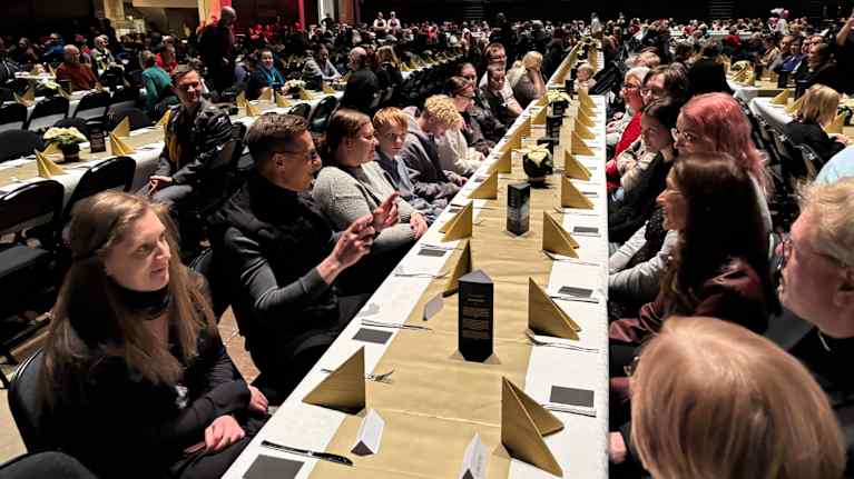 Runsaasti ihmisiä pitkän ruokapöydän ääressä.