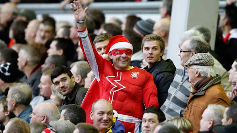 Liverpoolin fani on pukeutunut jalkapallokatsomossa punaiseen supersankariasuun ja tonttulakkiin.