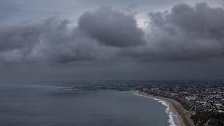 Ilmakuva rantaviivasta Kaliforniassa, taivaalla tummia sadepilviä.