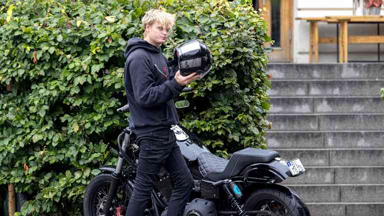 Marius Borg Høiby ottaa moottoripyöräkypärää päästään moottoripyörän vieressä.