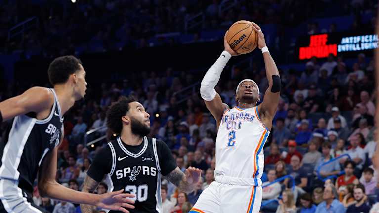 Oklahoman Shai Gilgeous-Alexander (2) yrittää korintekoa 25.12.2025. Taustalla seuraavat San Antonio Spursin Julian Champagnie ja Victor Wembanyama.
