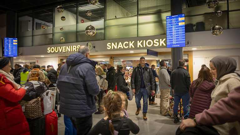 Ihmisiä kävelemässä lentokenttämiljöössä.