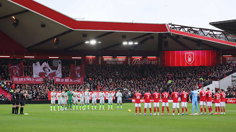 Nottinghamin ja Manchester Cityn pelaajat seisovat jalkapallokentällä riveissä antaen kunnioittavat aplodit edesmenneelle John Robertsonille.