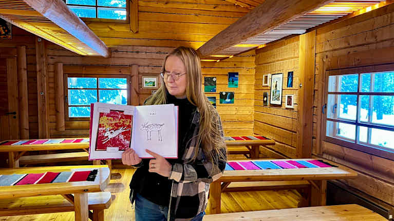 Nainen esittelee sarjakuvakirjaa.