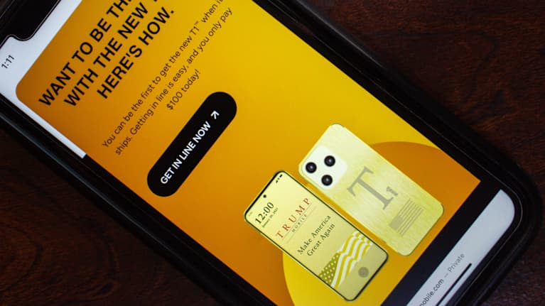 Puhelimen ruudulla on mainos kullan värisestä Trump T1 -puhelimesta.