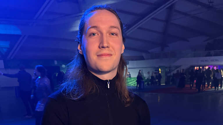 Nuori mies katsoo kameraan.