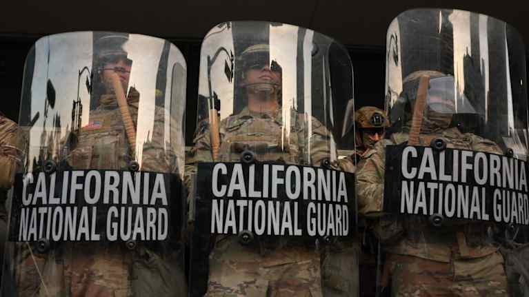 Maastopukuun pukeutuneita kansalliskaartin joukkoja seisoo rivissä käsissään läpinäkyvät mellakkakilvet ja pamput.