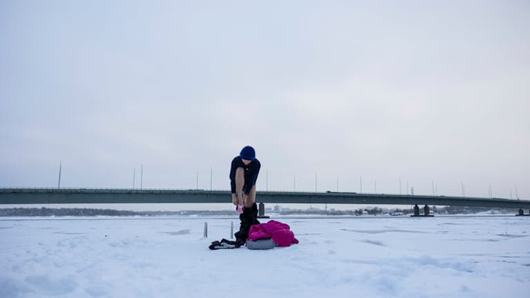 Talviuimari Sini Liu vaihtaa uimavaatteita päälle laiturilla. Takana Länsiväylän silta.
