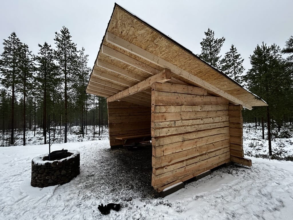 Hirsirunkoisen laavun sisäpuolella on jykevät penkit joka seinällä.
