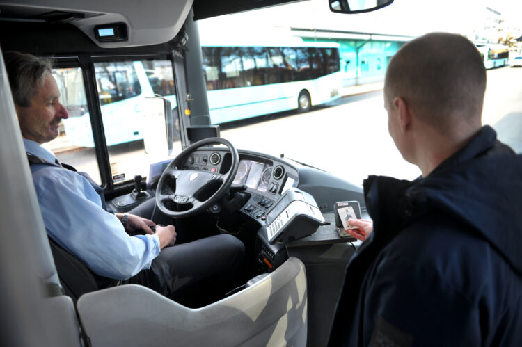 Kuvassa bussikuljettaja ja mies, joka on maksamassa bussilippua.