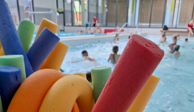 Värikkäitä uimapötkylöitä ja taustalla uima-allas