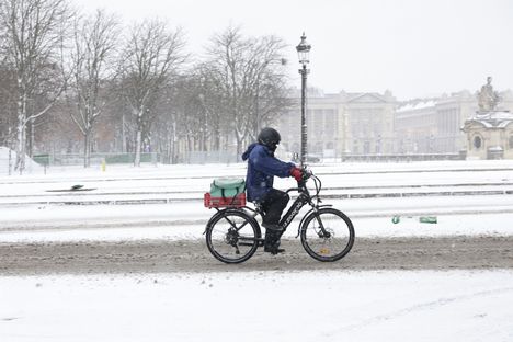 Pyöräilijä Pariisin loskaisella kadulla.