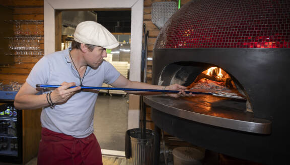 Tuukka Temonen laittaa pizzalapiolla pizzaa uuniin Ravintola Rehtorissa.