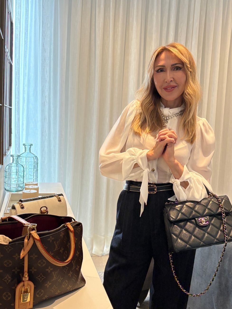 Nadja esittelee makuuhuoneessa käsilaukkujaan.