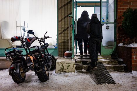 Imran Hossain ja Parvez Ahammed ja Rudyard Legaspi työntävät sähkömopoa sisään korjaamoon.