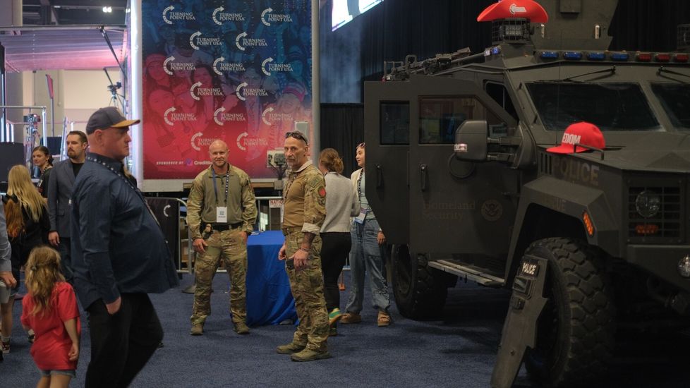 Yhdysvaltain sisäisen turvallisuuden ministeriön panssaroitu ajoneuvo on esillä messuhallissa. Sen parkkeerauspaikka on sangen symbolinen: vieressä on rekkalava, joka jäljittelee surmatun Charlie Kirkin yliopistoesiintymisten näyttämöjä. Yksi esiintymisistä koitui Kirkin kohtaloksi.