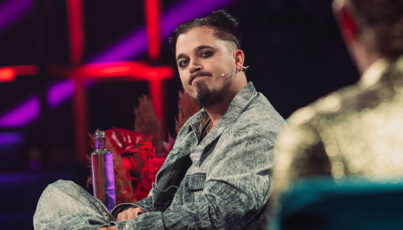 Käärijä istuu vihreällä sohvalla.