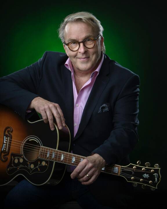 Joel Hallikainen kitara sylissään.