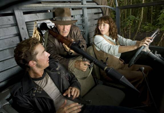 Shia LaBeouf, Harrison Ford ja Karen Allen auton kyydissä elokuvan kohtauksessa.