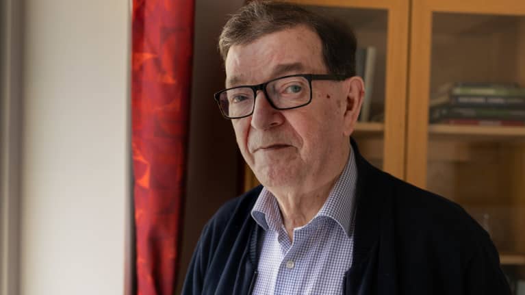 Kuvassa Paavo Väyrynen katsoo kohti kameraa kodissaan.