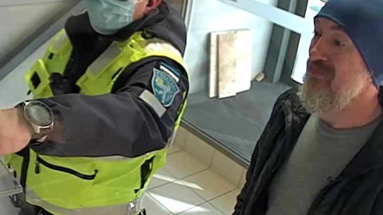 Pipopäinen mies poliisi vierellään.