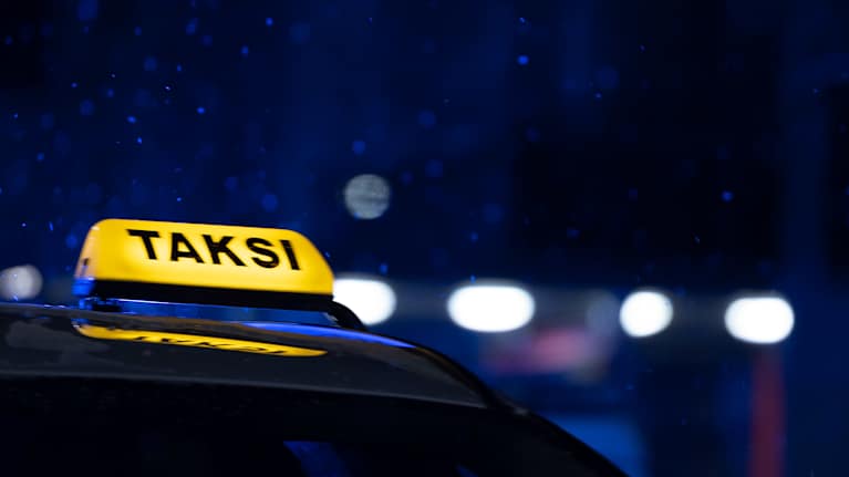 Valaistu taksikyltti pimeässä yössä.