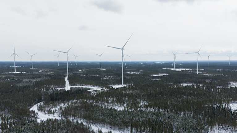 Tuulivoimaloita metsäisessä ja talvisessa maisemassa.