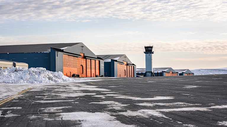 Hangarer och ett flygledartorn i ett snöigt landskap.