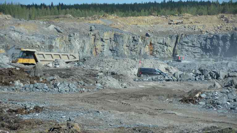 Maansiirtoauto ja pakettiauto avolouhoksella.