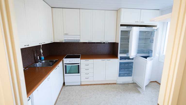 Tyhjä keittiö kaappeineen ja kodinkoneineen.