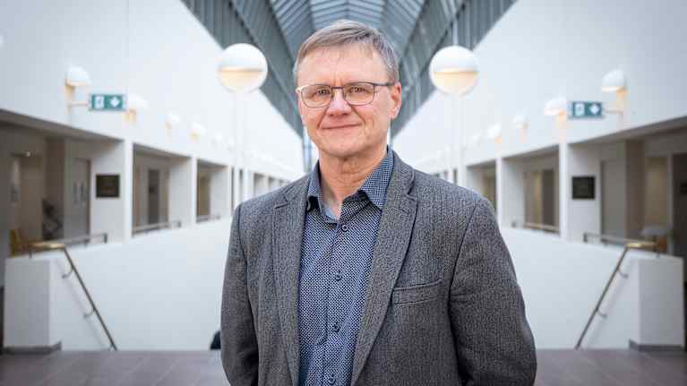 Mies katsoo hymyillen kameraan.