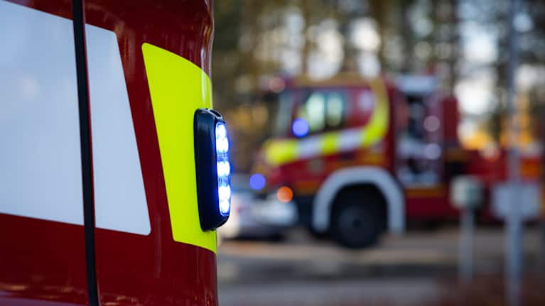 Paloauton sininen vilkkuva valo. Taustalla toinen paloauto.